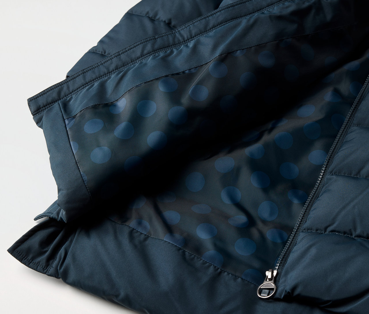 Egy gyermek termokabát részlete kék, pöttyös béléssel és cipzárral.