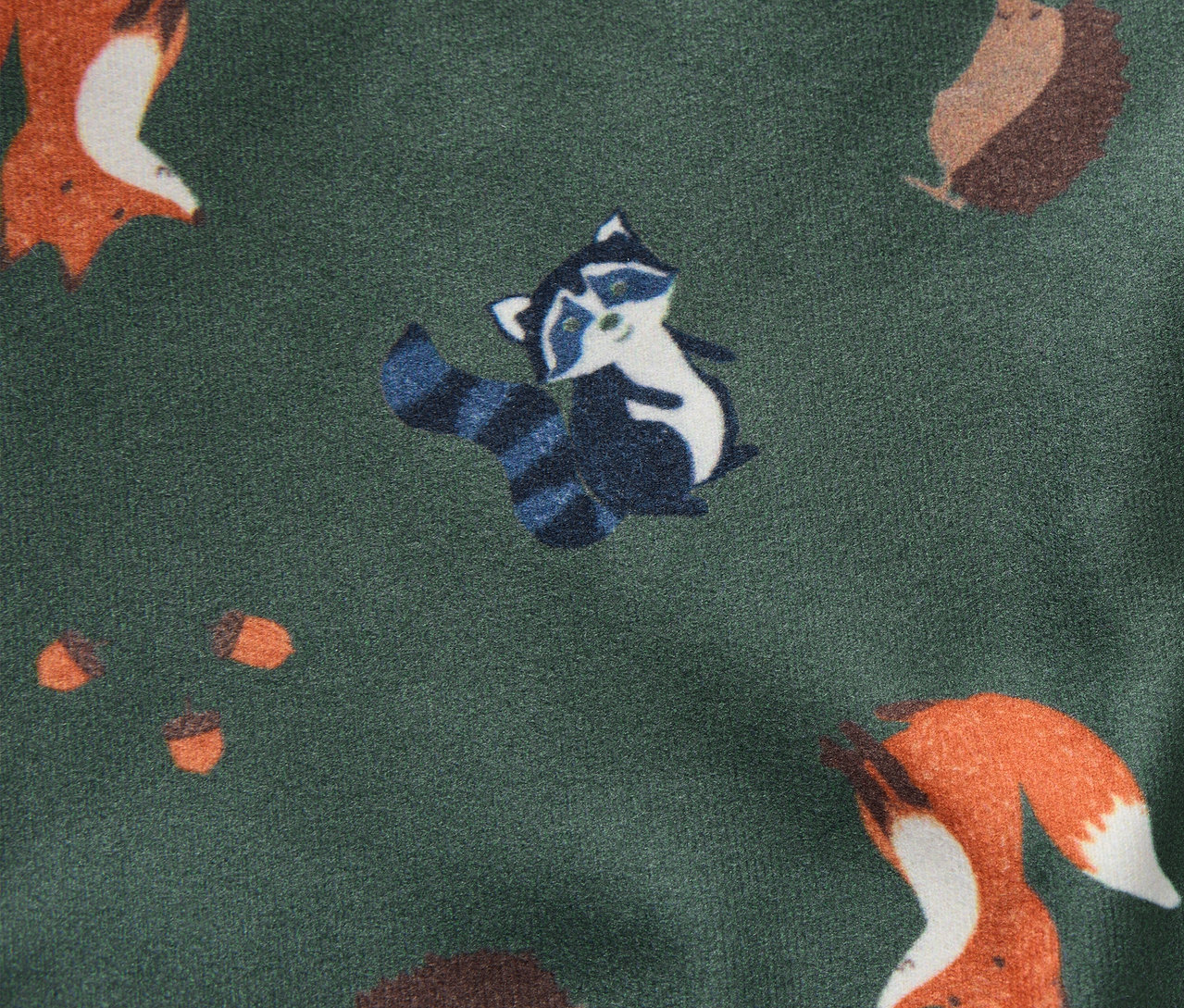 Mintás gyerek kifordítható bebújós sapka rókákkal, mosómedvékkel, sünökkel és makkokkal zöld háttéren.