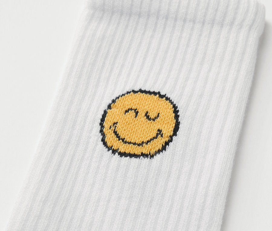 Egy fehér SMILEYWORLD® gyerek sportzokni részlete (5 pár SMILEYWORLD® gyerek sportzokni), mosolygó mintával.