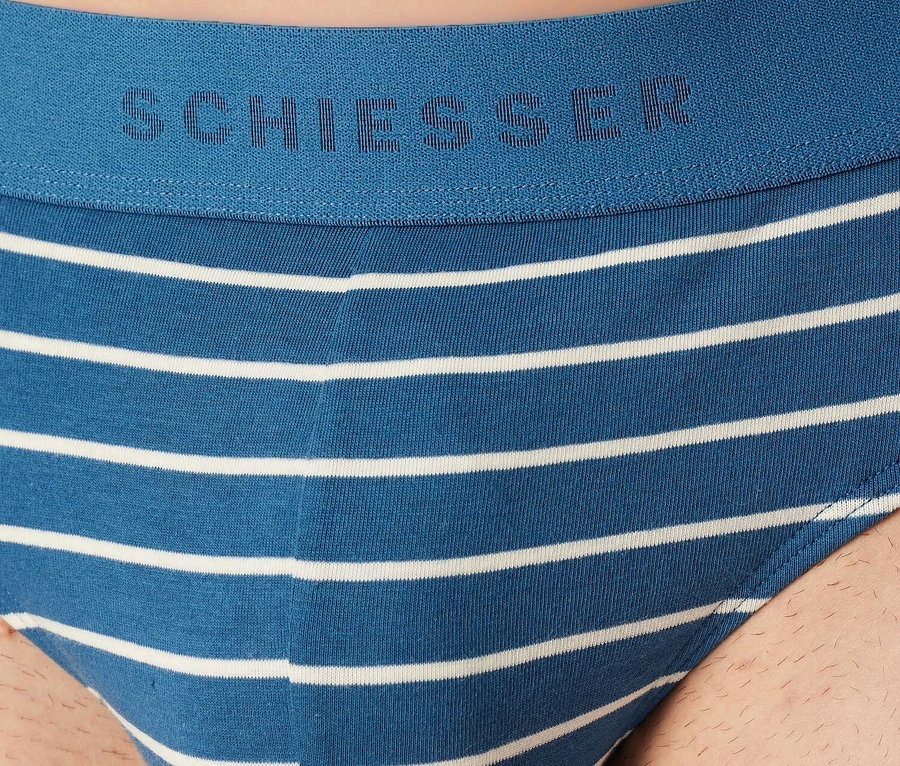 Egy kék Schiesser férfi alsónadrág részlete fehér vízszintes csíkokkal.