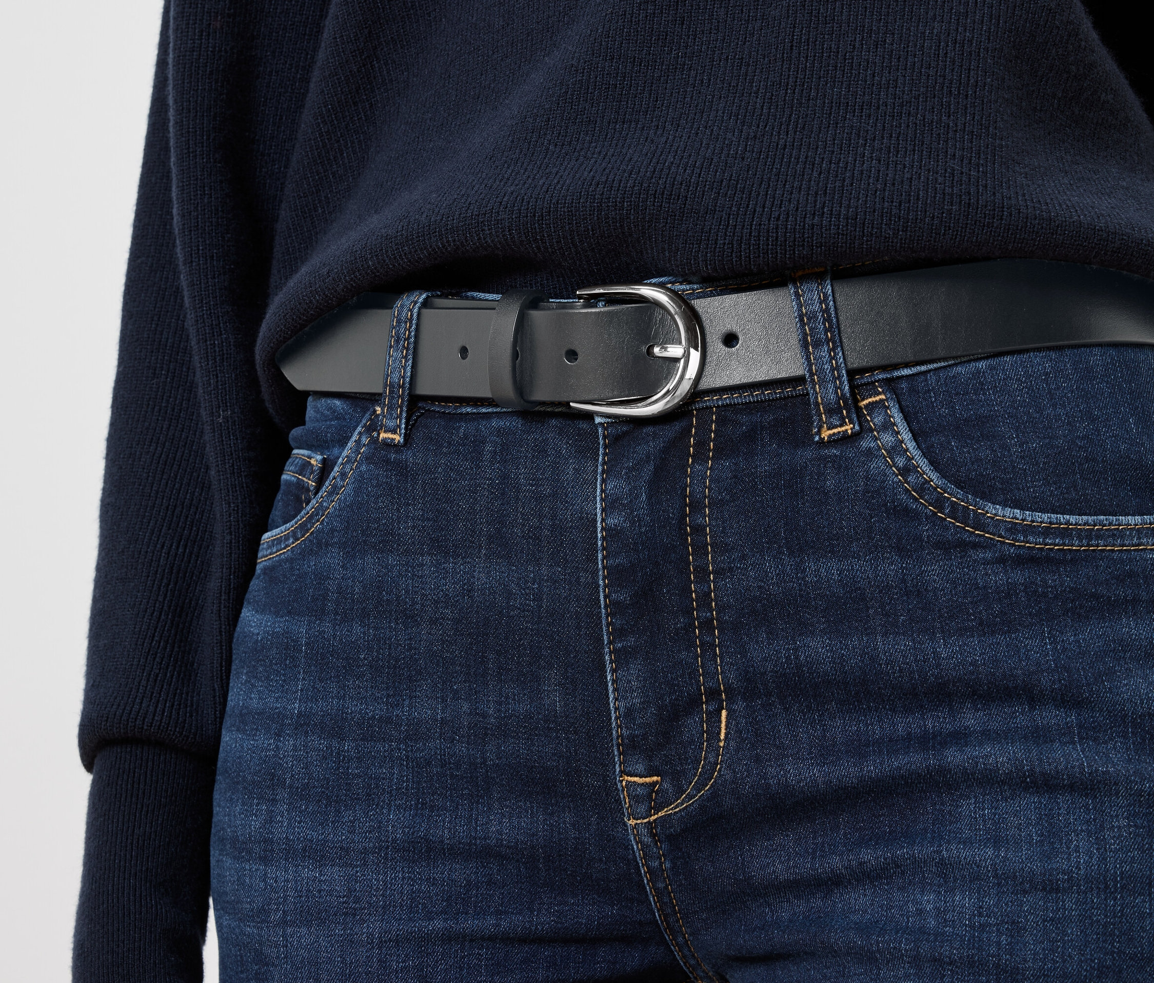 Fekete bőröv kék farmeren.