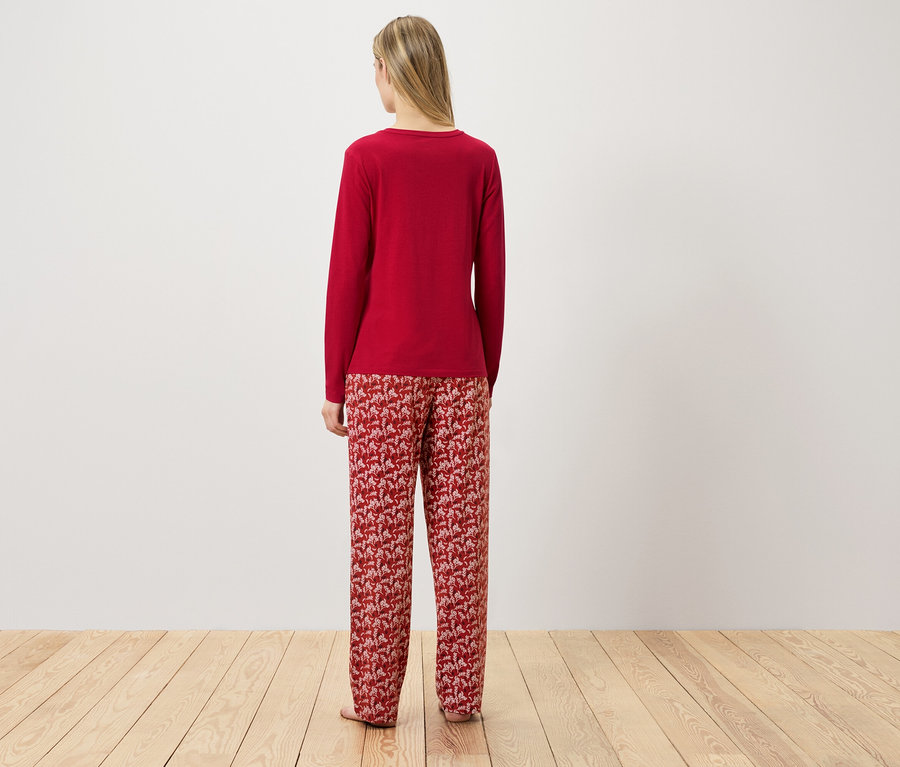 Egy nő áll háttal a kamerának, és piros pizsamát visel.