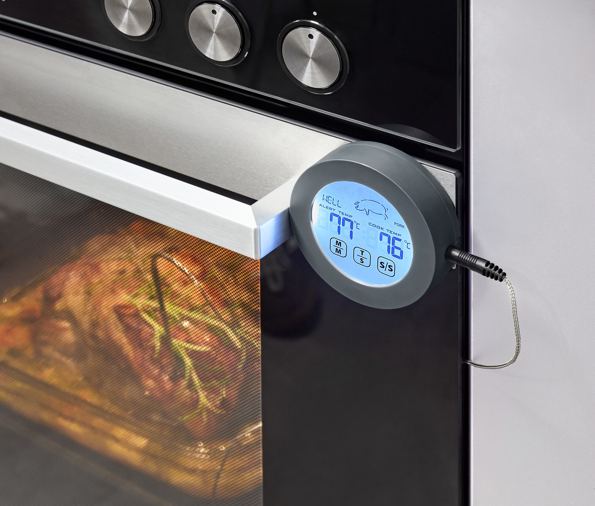 Sütő étellel belül és hőmérővel az ajtaján.