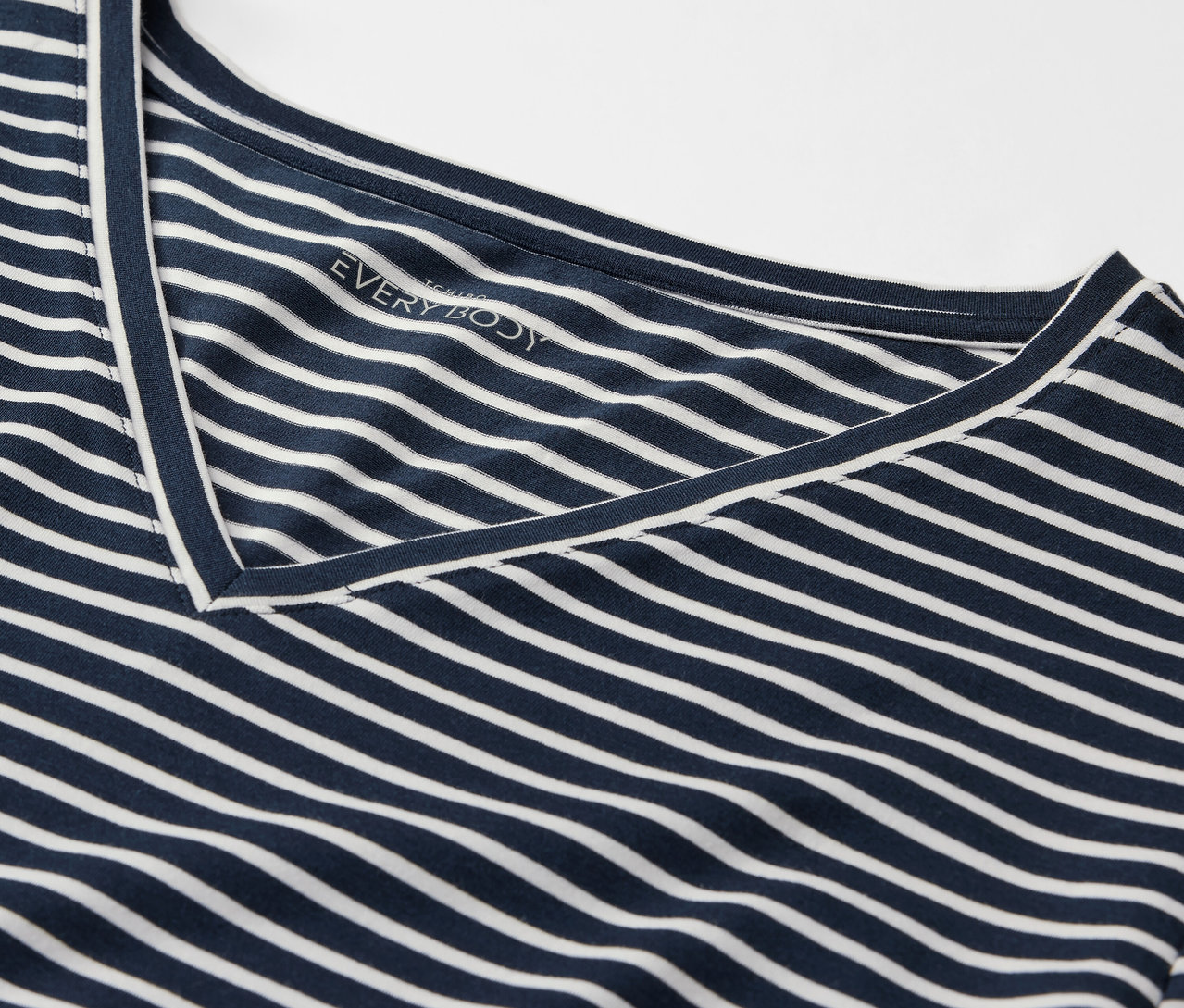 Egy kék-fehér csíkos, V-nyakú póló részlete.