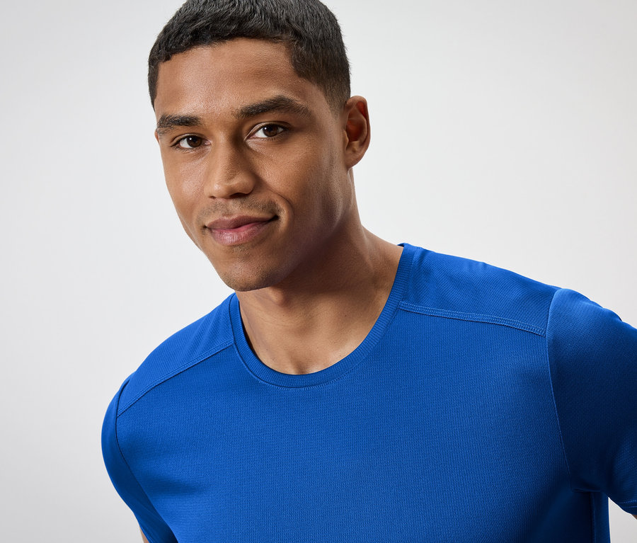 Portré egy mosolygó férfiról kék pólóban.