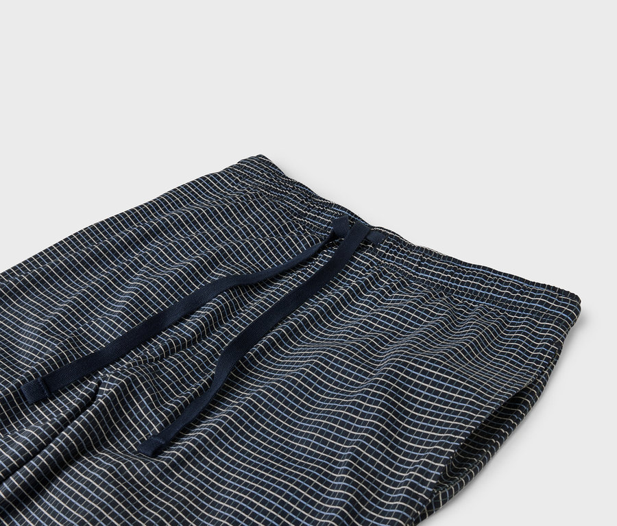 Részlet egy tengerészkék kockás nadrágról, elasztikus derékpánttal és húzózsinórral.