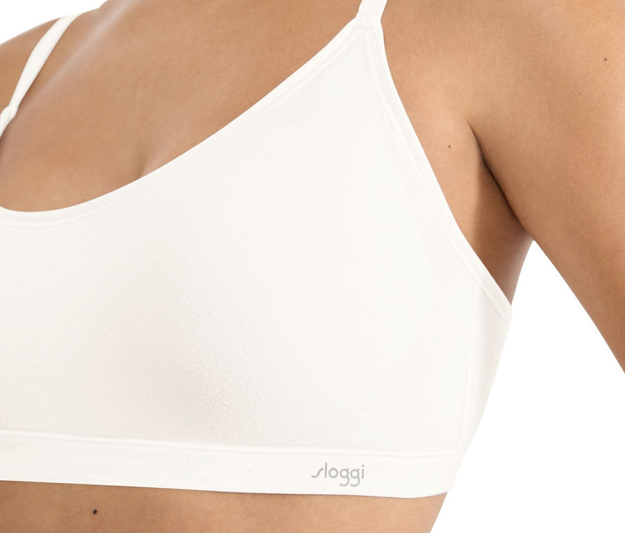 Közeli kép egy fehér, vékony pántos Sloggi melltartót viselő nőről.