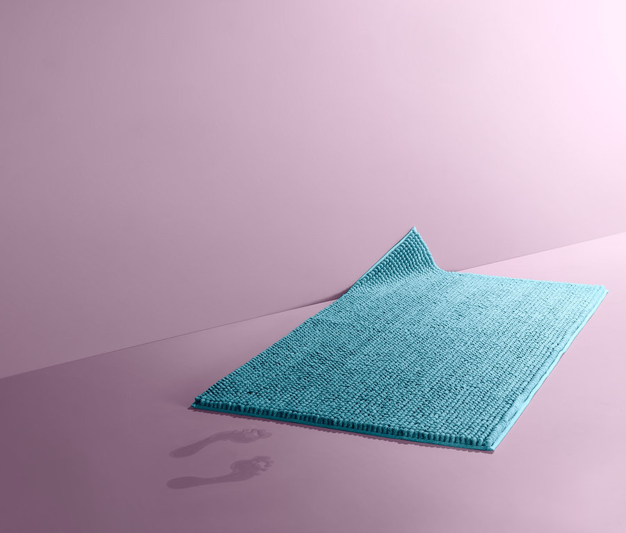 Türkiz kádkilépő, kb. 70 x 120 cm, a padlón fekszik nedves lábnyomok mellett.