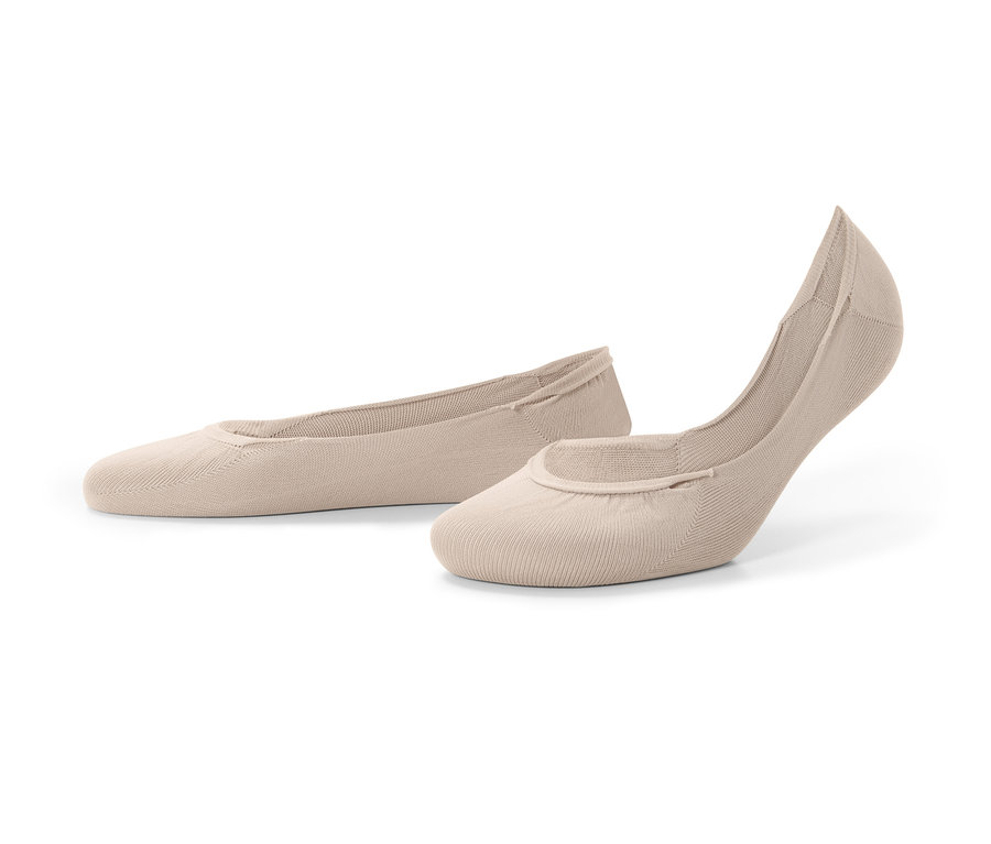 Két pár testszínű balerina titokzokni fekszik a háttéren.