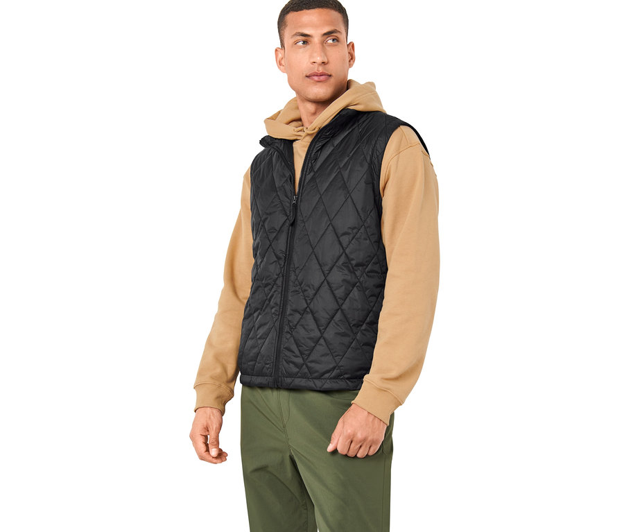 Férfi visel egy fekete mellényt egy 3 az 1-ben túrakabátból és olívazöld nadrágot.