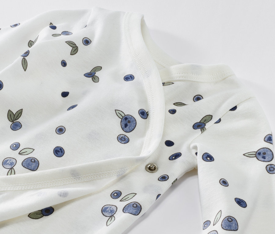 Egy áfonyás mintázatú, hosszú ujjú pamut body közelképe.