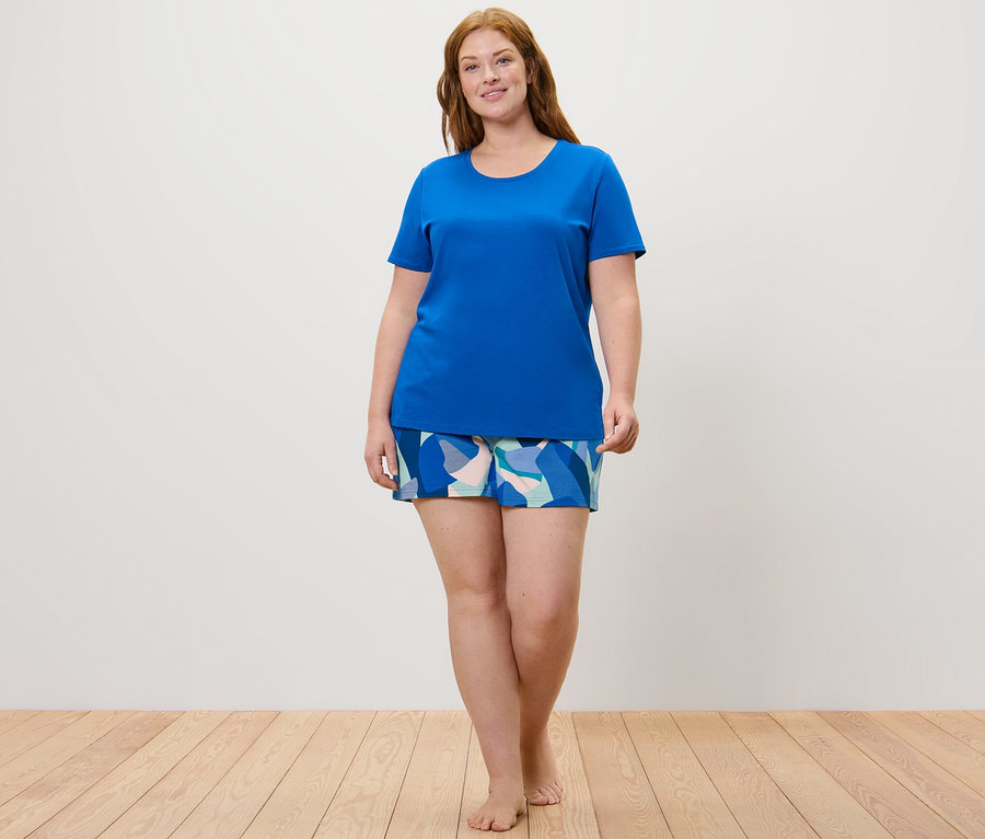 Nő visel mintás/kék női rövidnadrágos pizsamát.