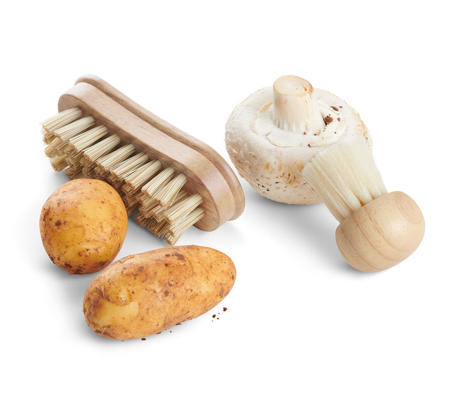 Két burgonya és egy csiperke gomba két zöldségtisztító kefe mellett.