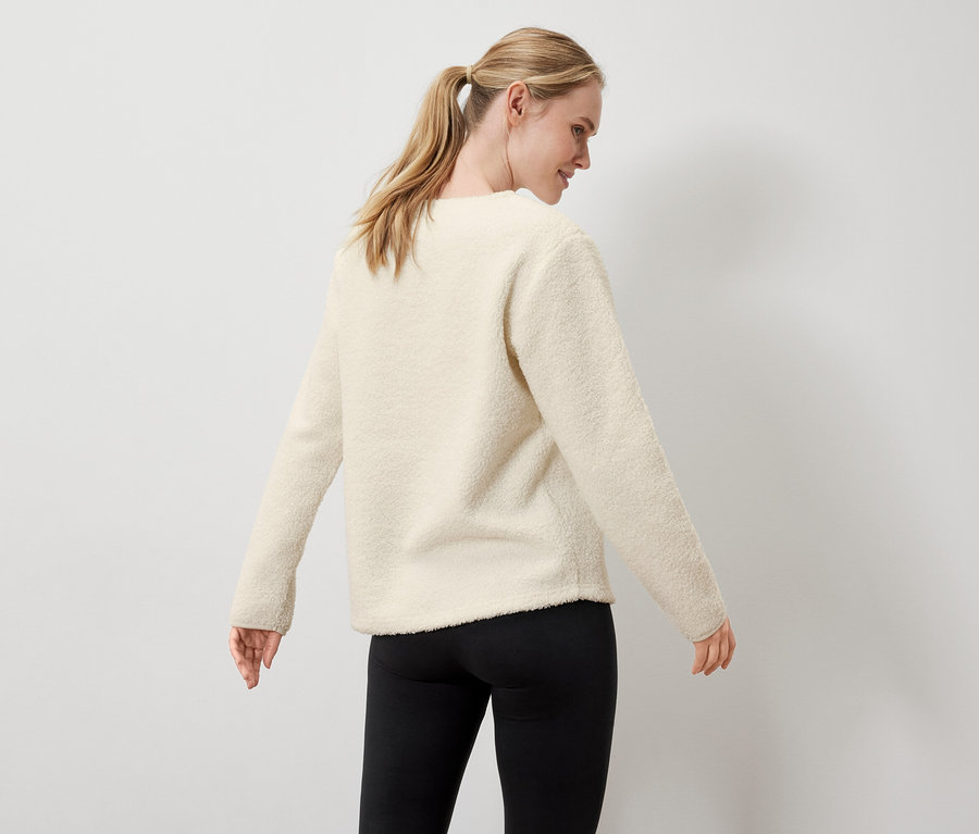 Nő krémszínű pulóvert és fekete leggingset visel.