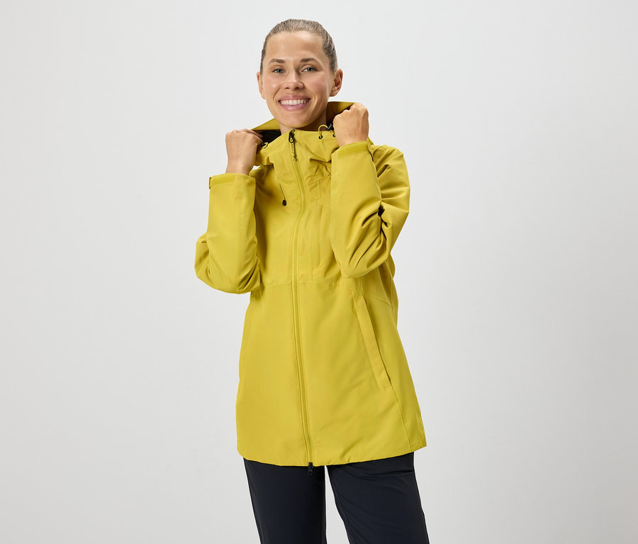 Nő igazítja a sárga, cipzáras kabátja kapucniját.