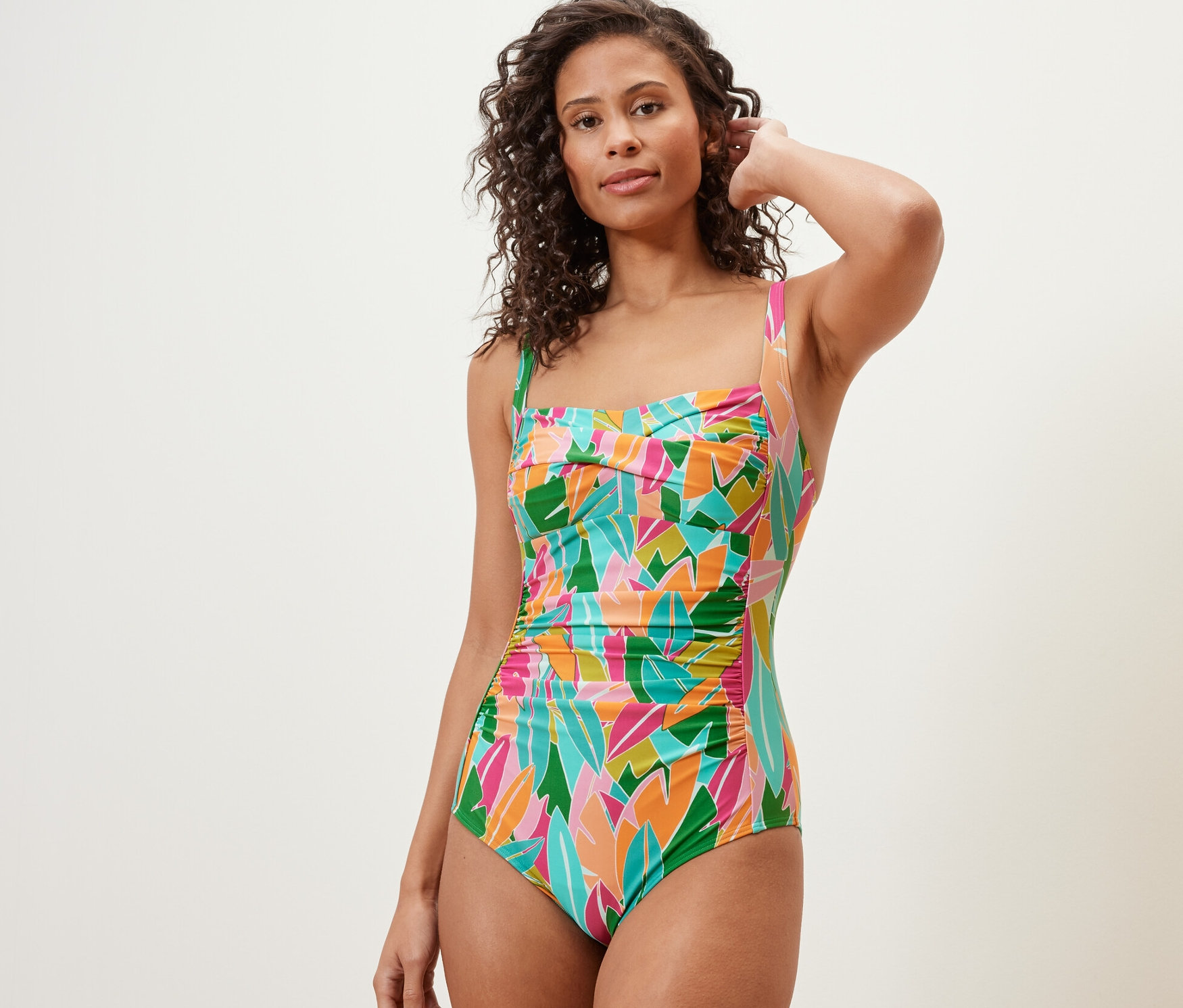 Nő pózol egy színes, alakformáló fürdőruhában.