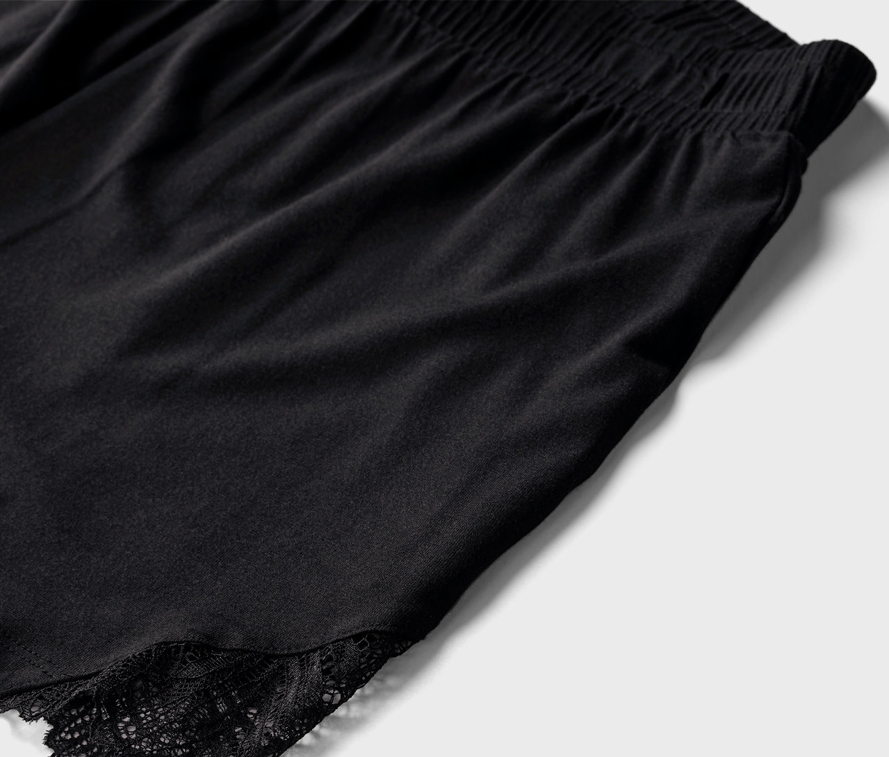 Egy fekete, csipkés rövid pizsama részlete.