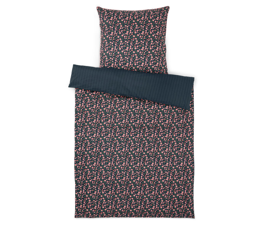 Virágmintás ágynemű és egyszínű, csíkos ágytakaró fehér háttér előtt.