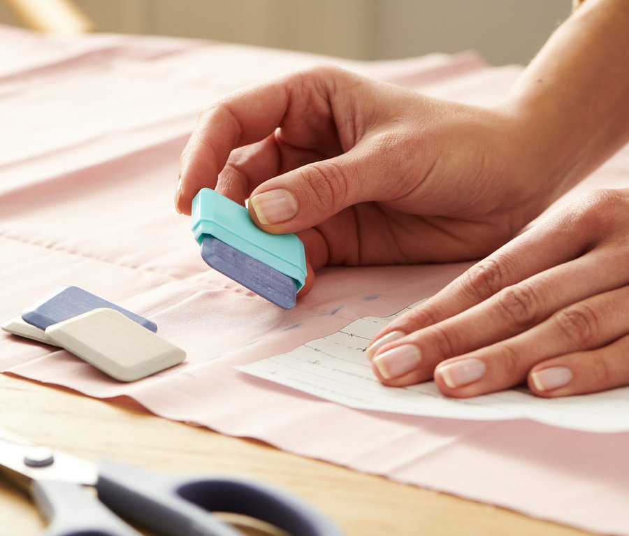 Nő szabókréta segítségével rajzol szabásmintát az anyagra.