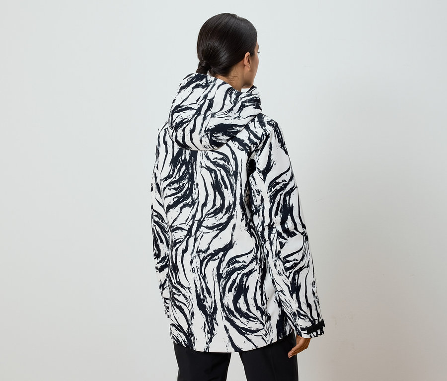 Hátulról látható egy lófarokkal rendelkező nő, aki fekete-fehér mintás, kapucnis kabátot visel.