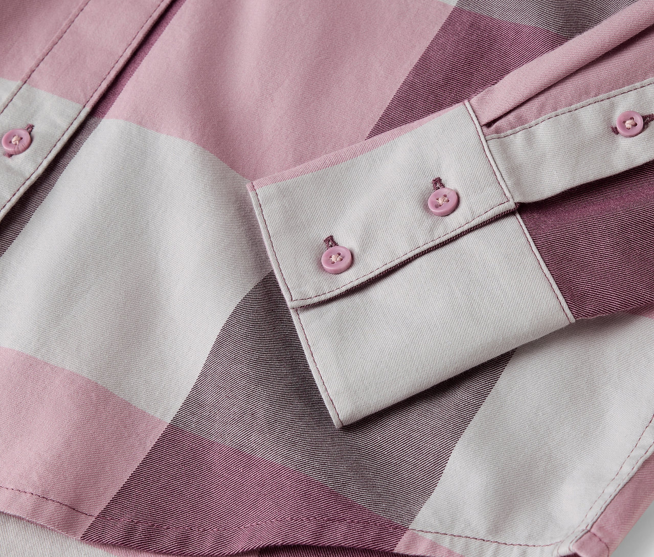 Egy rózsaszín-fehér kockás ing részlete gombokkal.