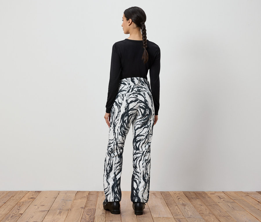 Hátulról látható nő fekete hosszú ujjú felsőben és fehér-fekete mintás nadrágban.