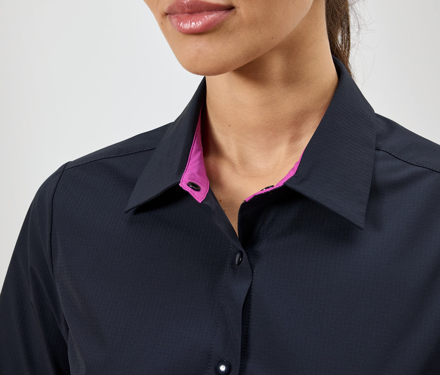Közeli kép egy nőről, aki sötétkék inget visel rózsaszín gallérral.