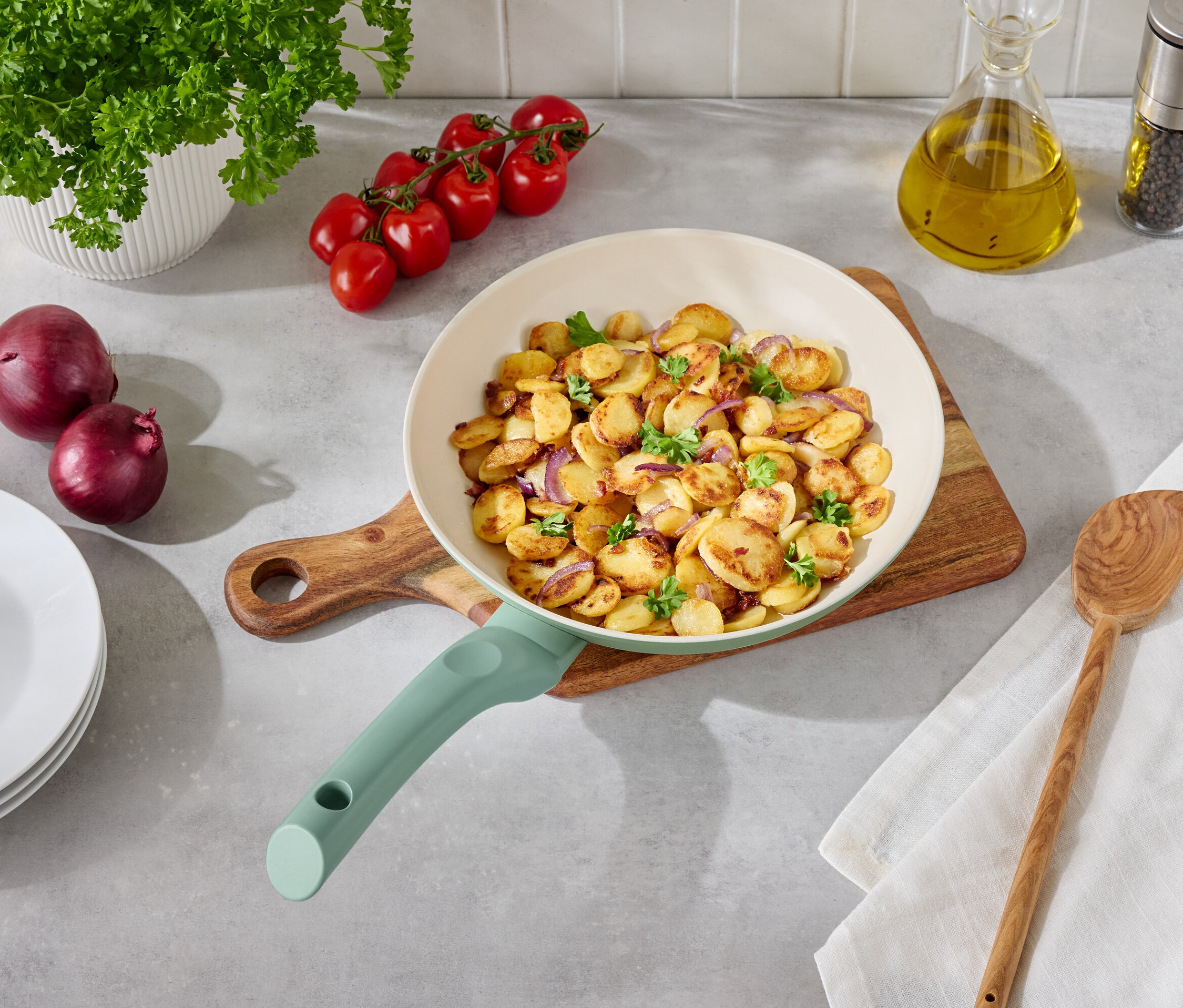 Sült burgonya hagymával és petrezselyemmel egy serpenyőben egy faasztalon köretekkel.