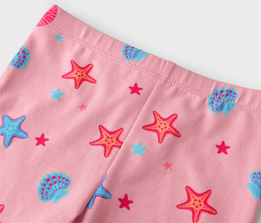 Közelkép egy rózsaszín leggingsről tengericsillag, kagyló és csillag mintákkal.