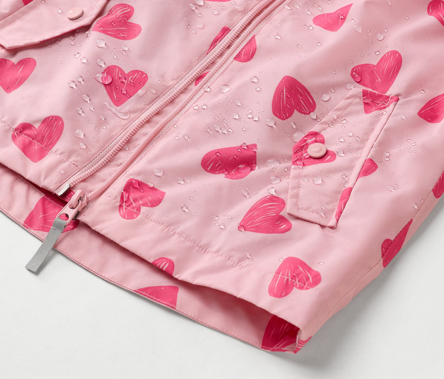 Egy rózsaszín, szívecskés mintájú esőkabát közeli képe, vízcseppekkel.