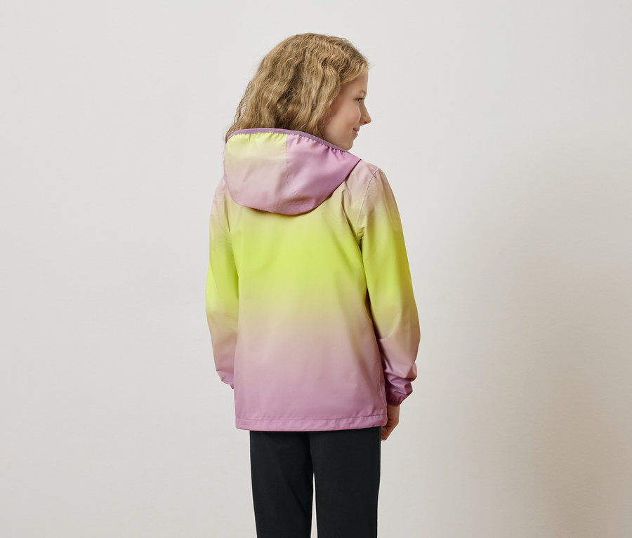 Hátulnézet egy hullámos hajú fiatal lányról, aki sárga-rózsaszín kapucnis kabátot és fekete nadrágot visel.