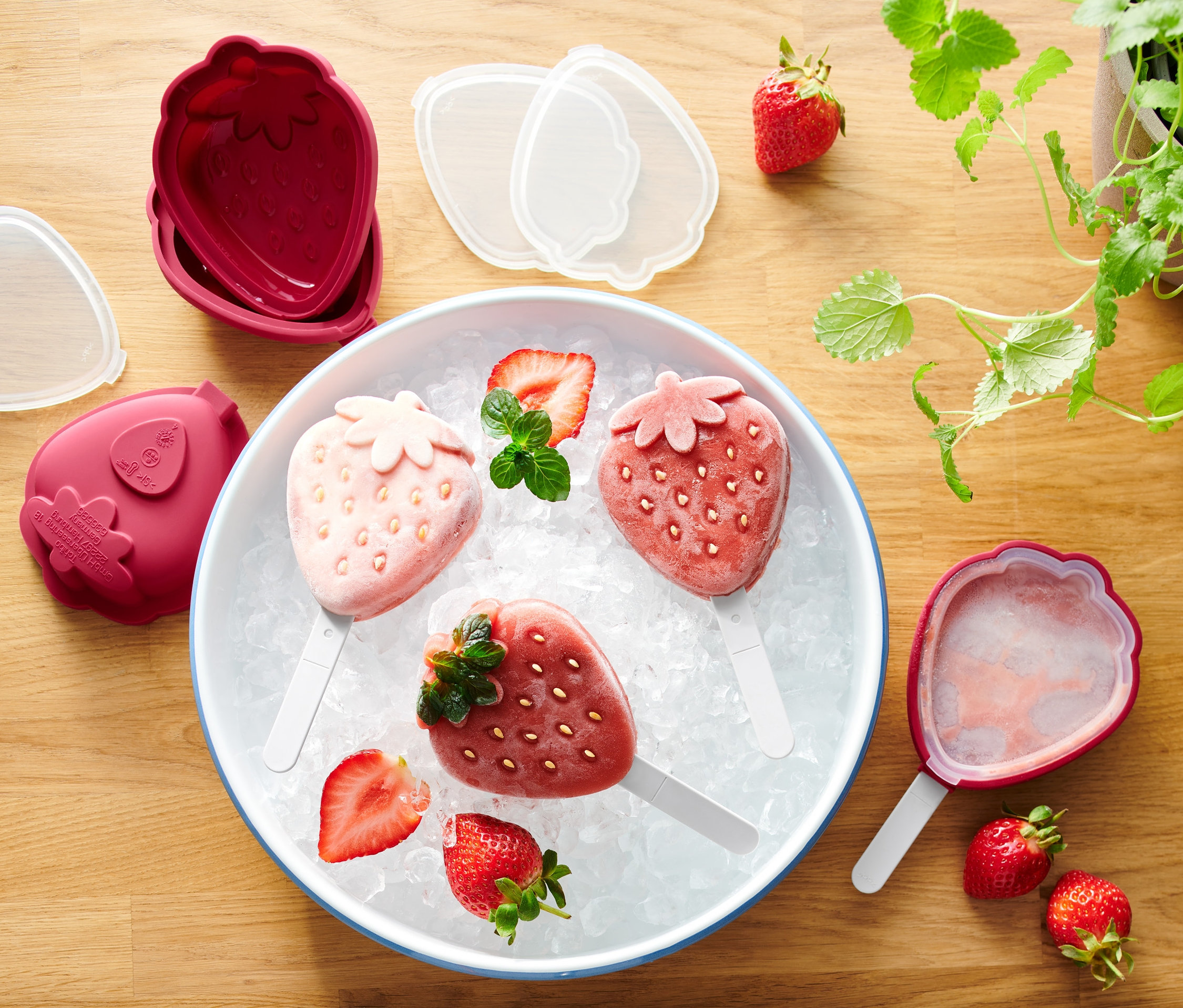 Három epres jégkrém a jégen egy tálban, a 4 szilikon jégkrémkészítő eperforma szett mellett.