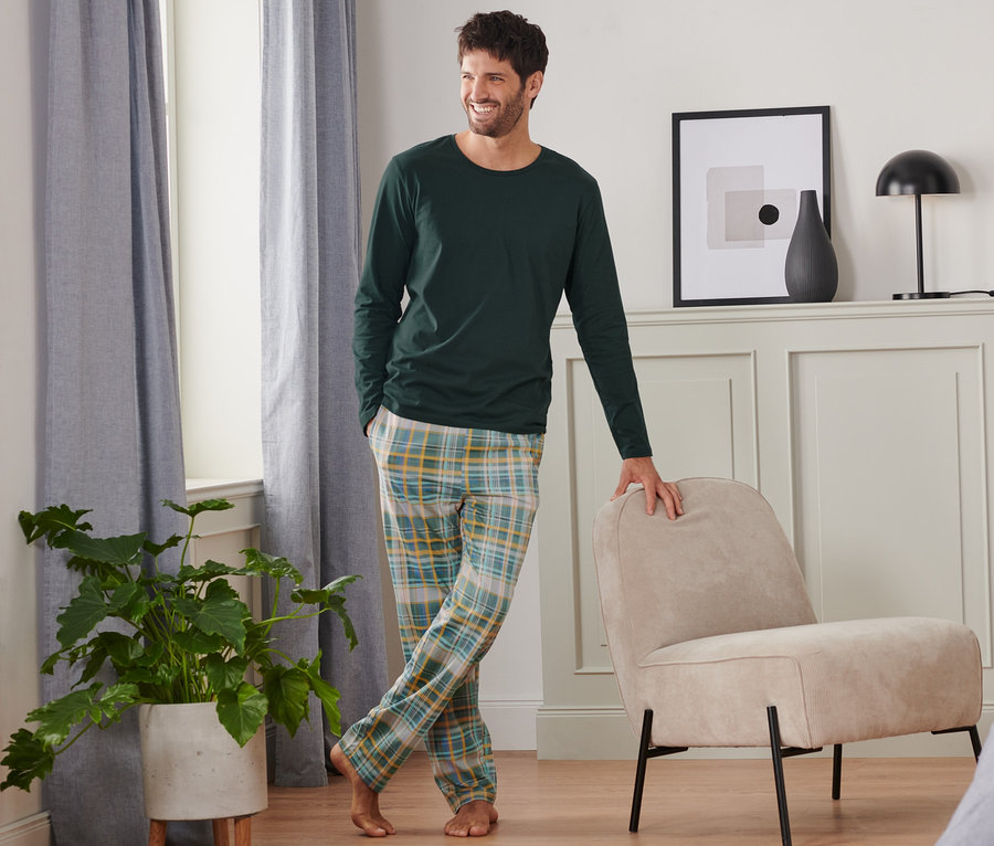 Férfi pizsamában áll a hálószobában.