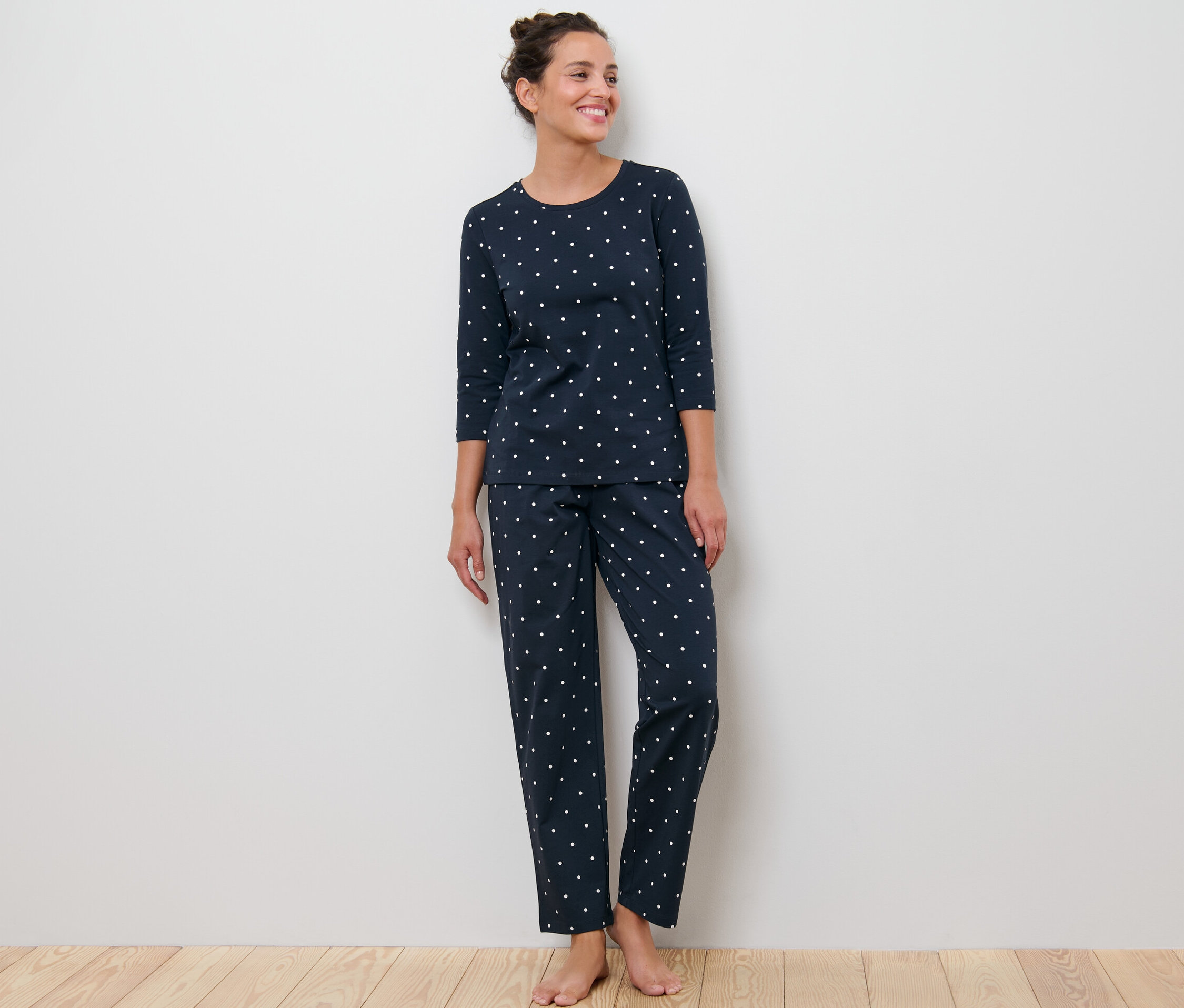 Egy nő áll pöttyös, sötétkék pizsamában.