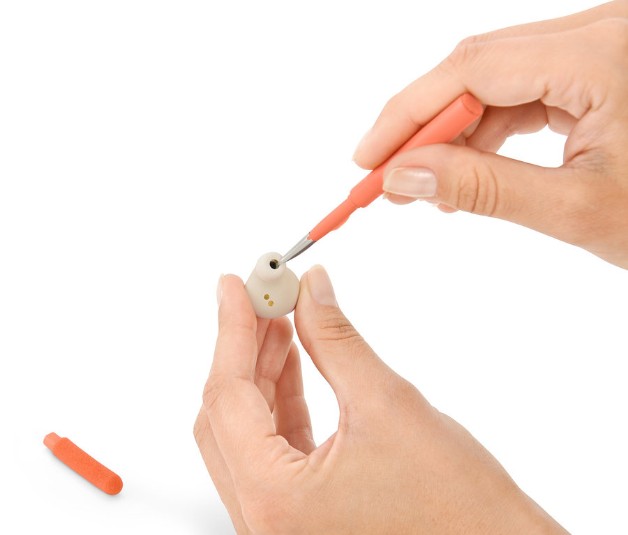 Kezek tisztítanak egy fülhallgatót egy 4 az 1-ben elektronikai eszköz tisztítóval.