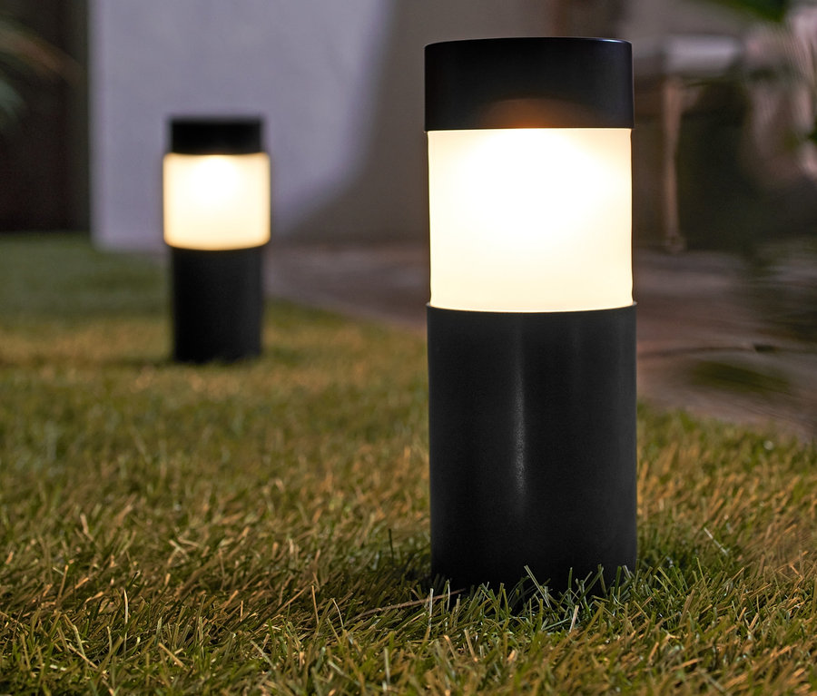 Két napelemes kerti lámpa a füvön.