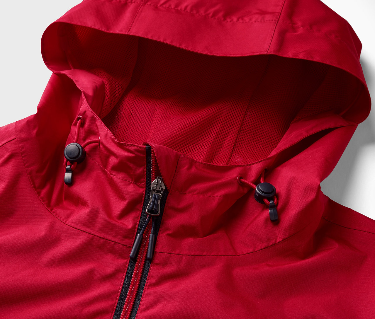 Egy piros esőkabát részlete cipzárral és kapucnival.
