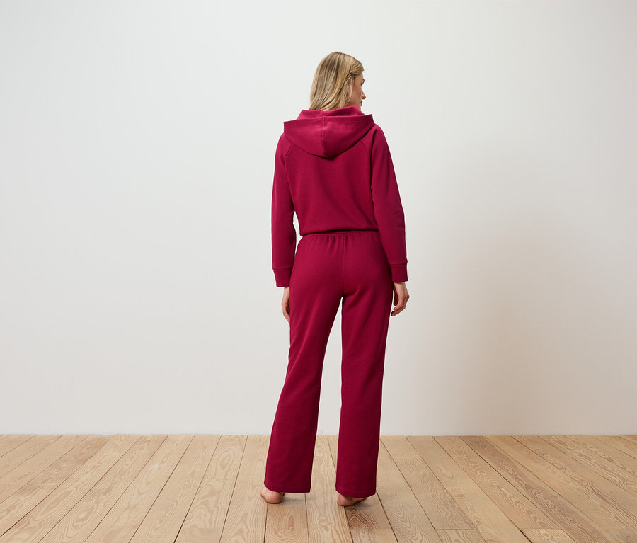 Nő áll háttal, bordó kapucnis tréningruhában.