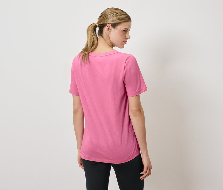 Nő visel rózsaszín pólót és fekete leggingset.