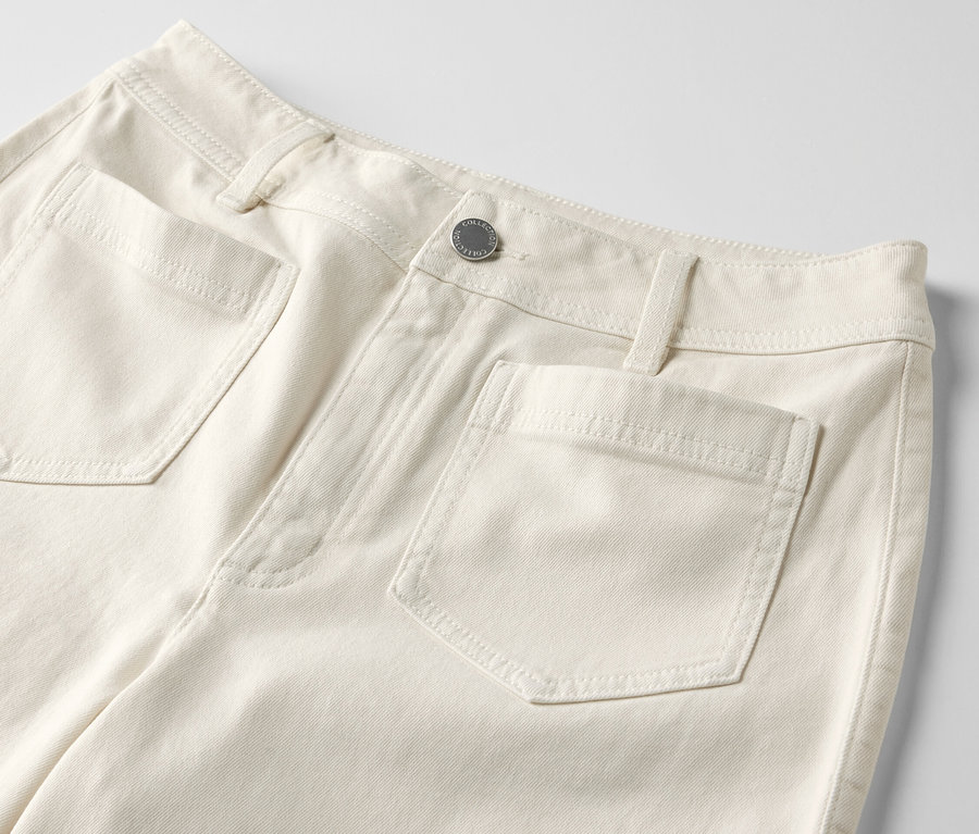 Egy krémszínű, »Cara« szabású, trapézszárú farmer részlete zsebekkel.