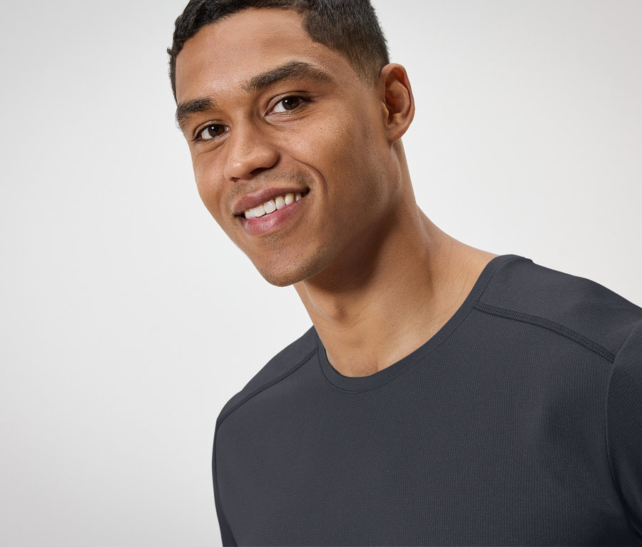 Portré egy mosolygó férfiról fekete pólóban.