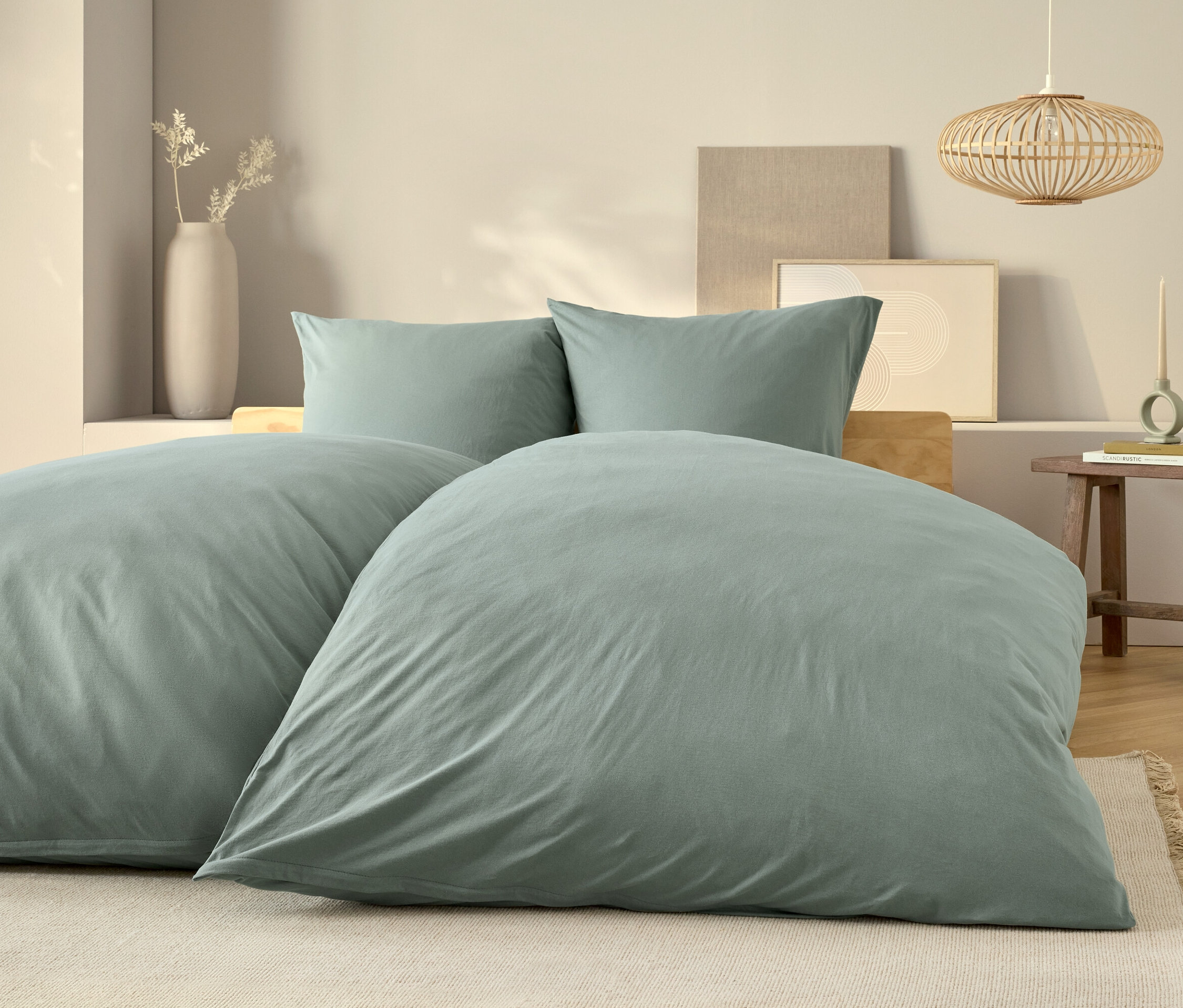 Világoskék ágynemű egy ágyon, két párnával és egy fa éjjeliszekrénnyel.