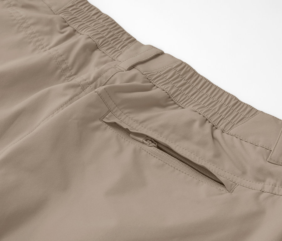 Egy bézs színű, 2 az 1-ben funkcionális nadrág részlete cipzáras zsebbel.