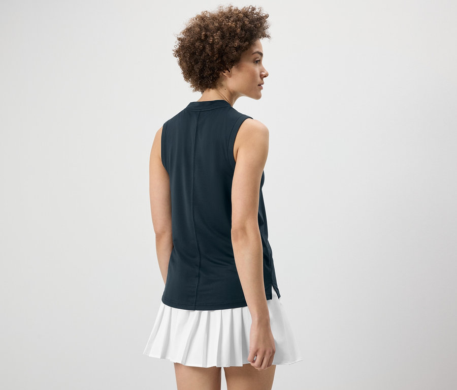 Hátulról látható nő sötétkék funkcionális felsőt és fehér szoknyát visel.