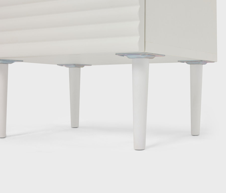 Egy fehér szekrény részletének képe, négy kúpos lábbal.