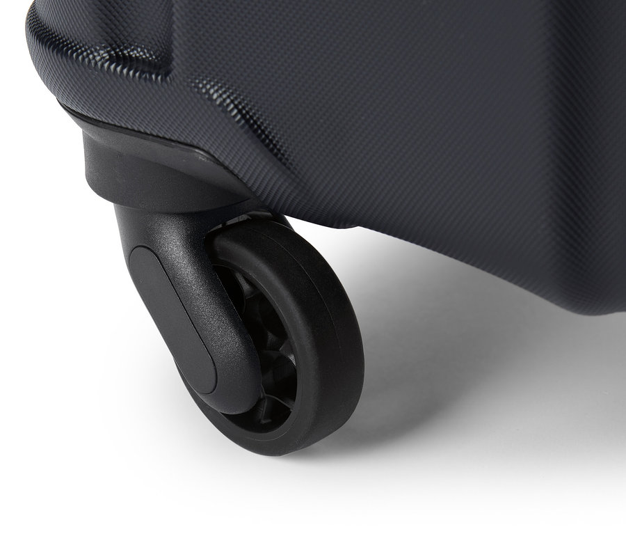 Egy fekete gurulós bőrönd kerekének közeli képe fehér háttéren.