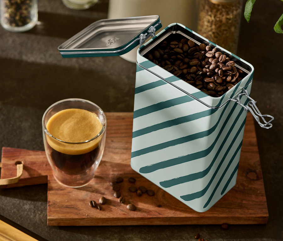 Egy pohár eszpresszó és egy nyitott, csíkos kávétartó doboz áll egy fa deszkán.