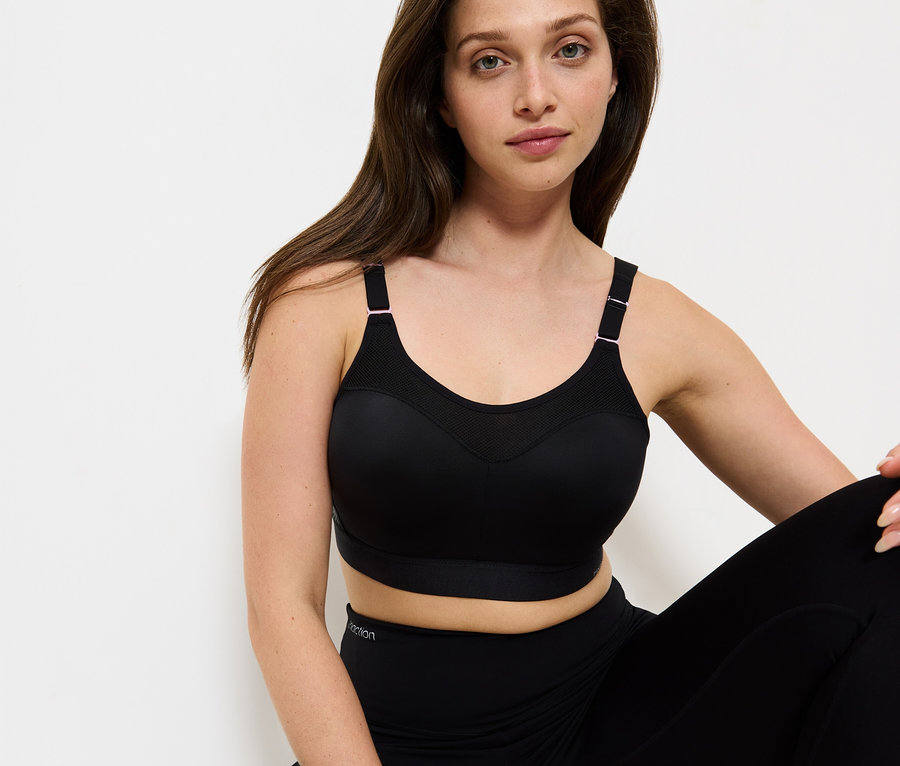 Nő ül, fekete sportmelltartót és leggingst visel.