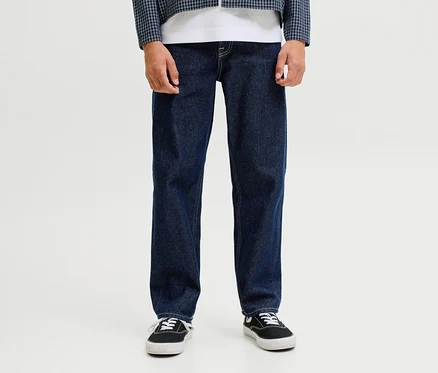 Egy személy sötétkék Jack&Jones JJOriginal Chris farmernadrágot, fehér pólót, kék-fehér kockás kabátot és fekete tornacipőt visel.