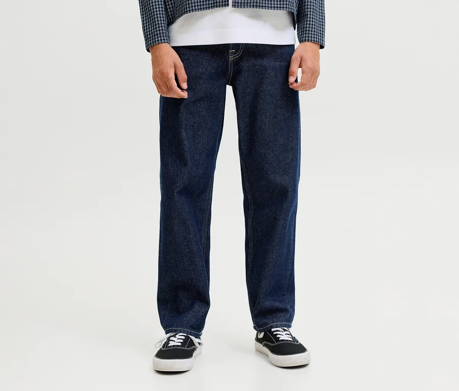 Egy személy sötétkék Jack&Jones JJOriginal Chris farmernadrágot, fehér pólót, kék-fehér kockás kabátot és fekete tornacipőt visel.